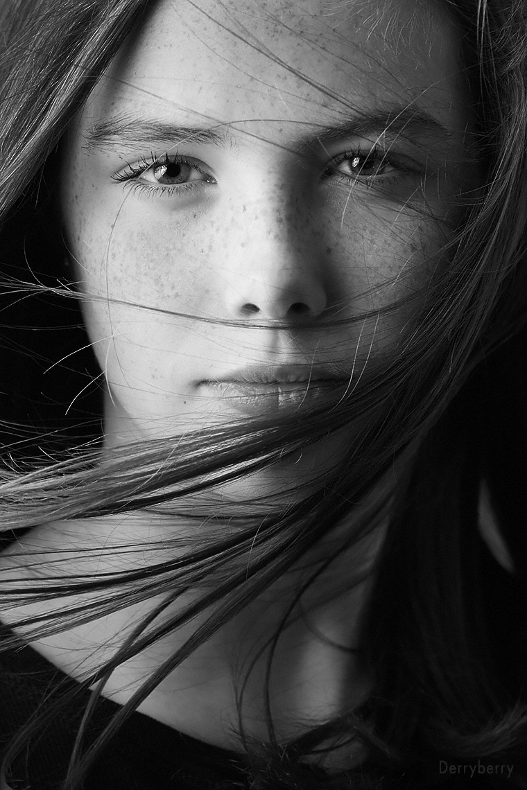 Black and white close up portrait of teen Katheryn Jones with her hair blowing in the studio  in Dallas, Texas by photographer John Derryberry Photography