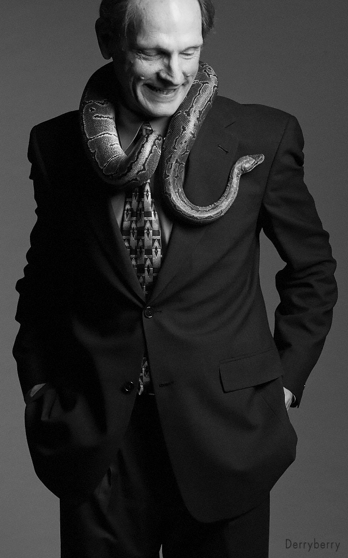 Black and white portrait of teacher at Greenhill Mr. Charlebois in a suit with a snake in Dallas, Texas by photographer John Derryberry Photography