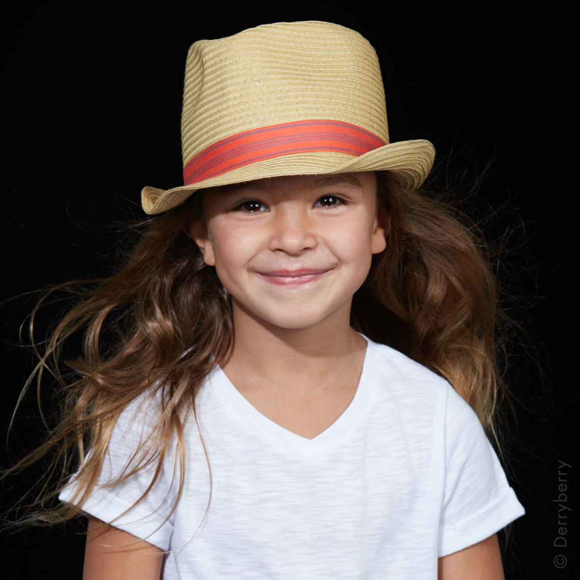 Stylish color studio  portrait of a little girl in a straw hat and white t-shirt