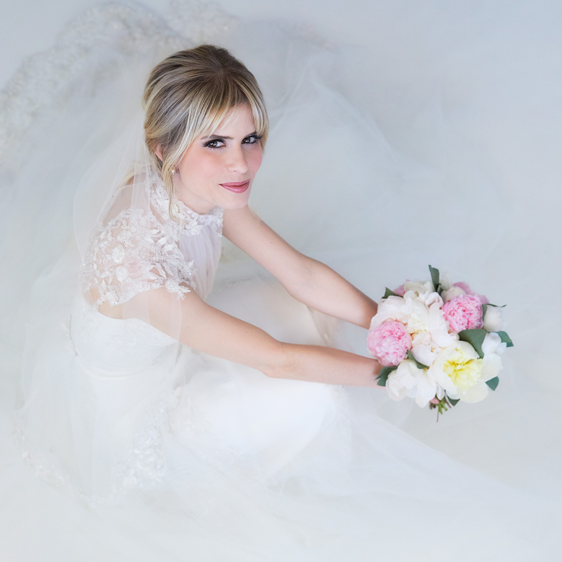 Color bridal Portrait of Carlson Young siting with her veil all around her and holding flowers
