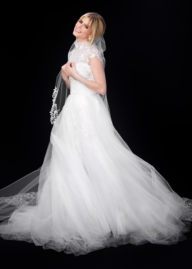 Color standing bridal portrait of Callie Young in the studio swishing on a black background.