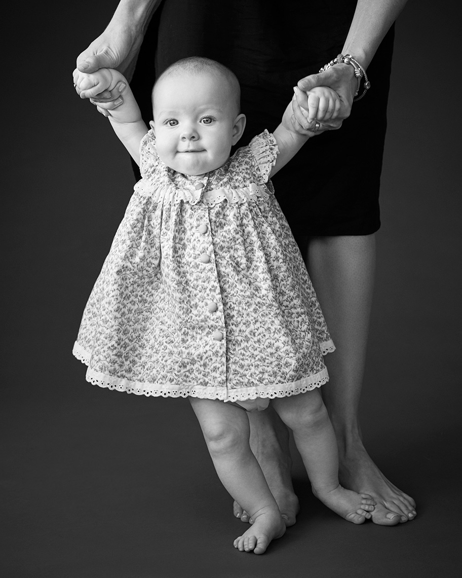 baby girl standing holding mom