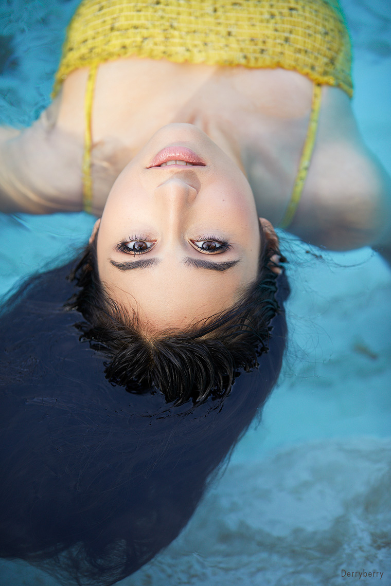 Color senior portrait of Emily Budarapu floating in a swimming pool from Greenhill school  on location  in Dallas, Texas by photographer John Derryberry Photography