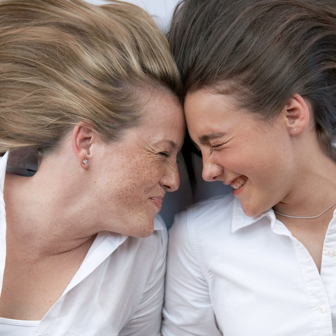Color portrait o of a mother and daughter smashing their heads together laughing in Dallas, Texas by photographer John Derryberry Photography