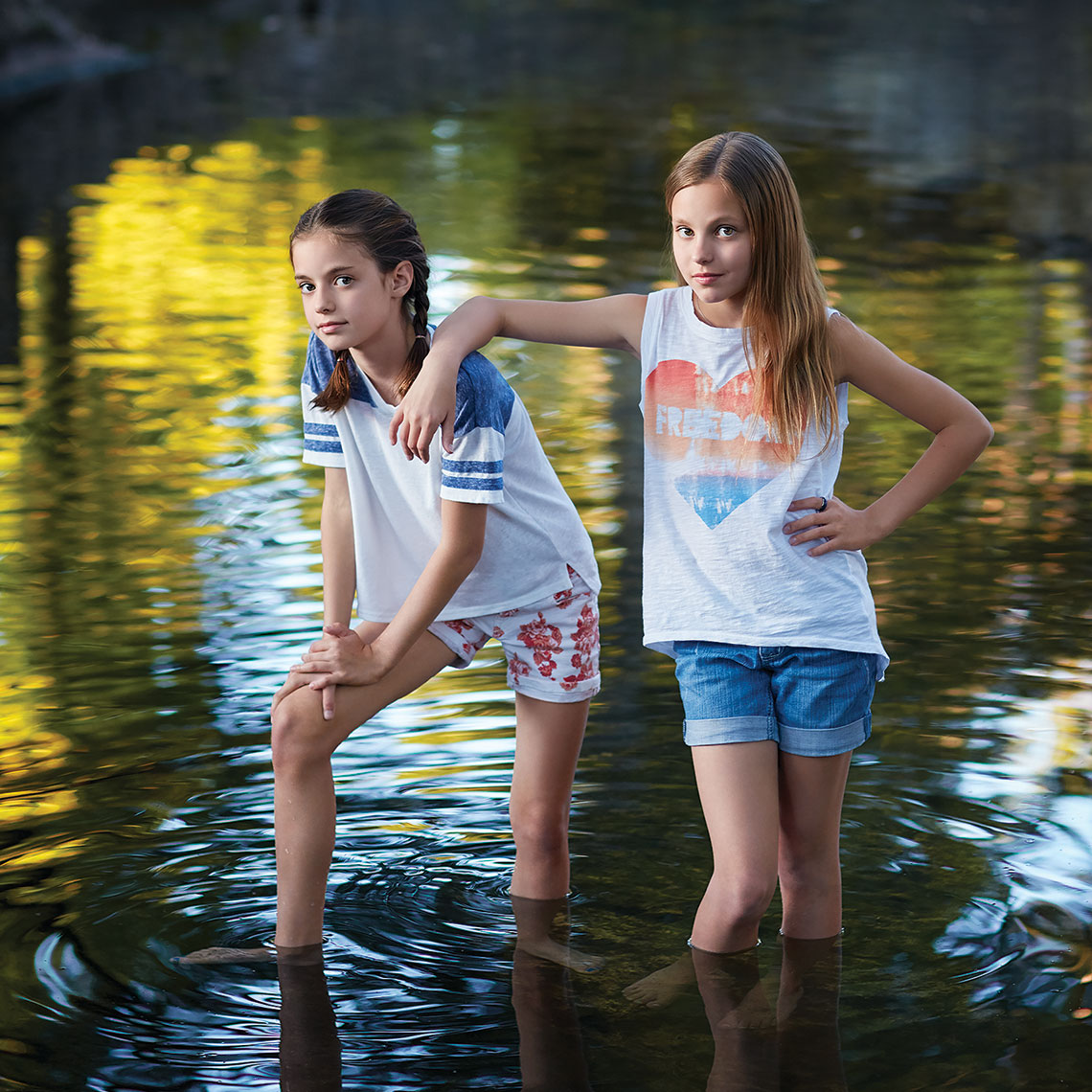 Color portrait of two sisters standing with an attitude in a creek in Highland Park by John Derryberry