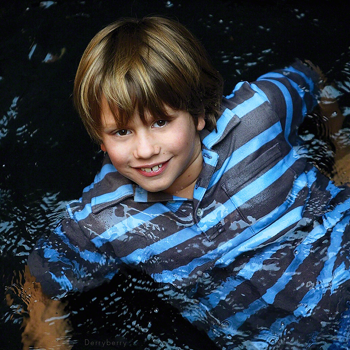 Color portrait of a little boy floating in a reflection pool or pond in his parents back garden in New York City upper east side