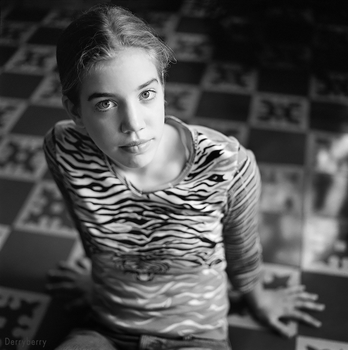 Portrait in black and white of tween girl in a tiger print shirt sitting on a beautiful vintage tile floor