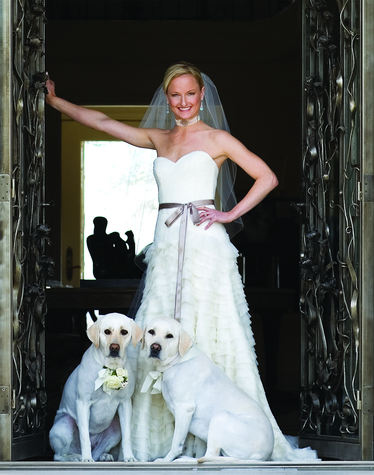 Color location portrait of Yost bride standing in the front doorway with her two white labs and a  behind her in Ft. Worth , Texas  by photographer John Derryberry Photography