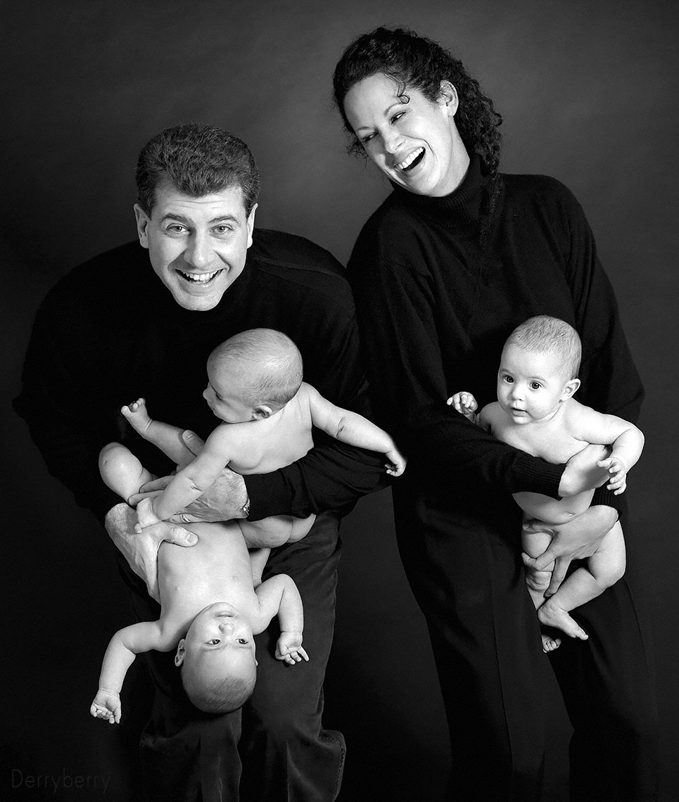 Portrait of  a family with a handful of triplet baby girls in the studio in black and white
